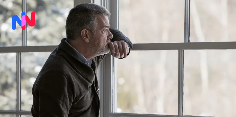 Un homme regardant par la fenêtre avec un regard triste